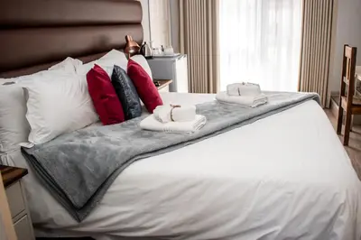 a white bed with towels on top of it at Balmoral Lodge in Bellville