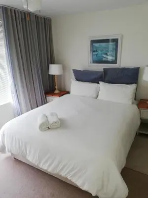 a bedroom with a large white bed with towels on it at Ocean View in Hermanus