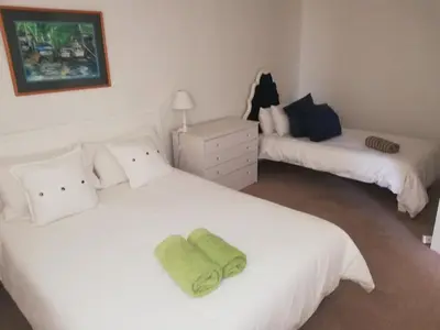 a bedroom with two white beds with a green towel on it at Ocean View in Hermanus