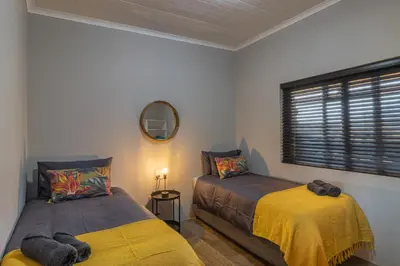 a bedroom with two beds and a mirror and a window at Steenbok farm cottages -Mongoose cottage in Wolseley