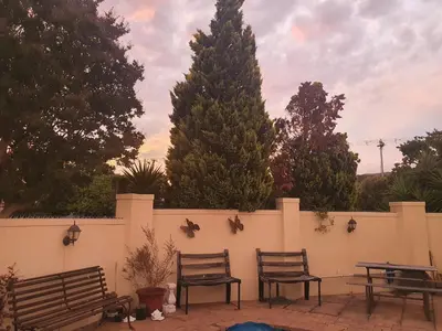 a fence with two chairs and a table and trees at DOTJJ B & B in Paarl