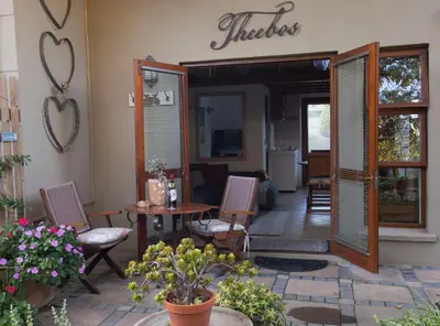 a patio with chairs and a table and a house at Theebos in Strand