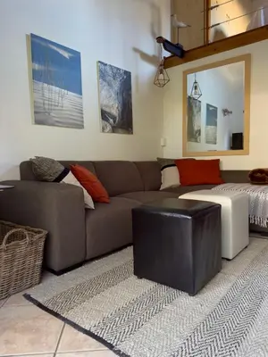 a living room with a couch and a ottoman at Theebos in Strand