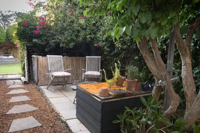 a garden with two chairs and a wooden table at Theebos in Strand