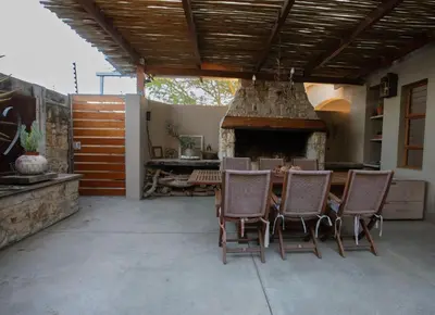 a patio with a table and chairs and a fireplace at Theebos in Strand