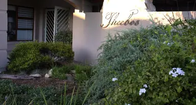 a house with flowers and a sign on the side of it at Theebos in Strand