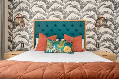 a bed with orange pillows and a blue headboard at Dolphin Beach E30 in Cape Town