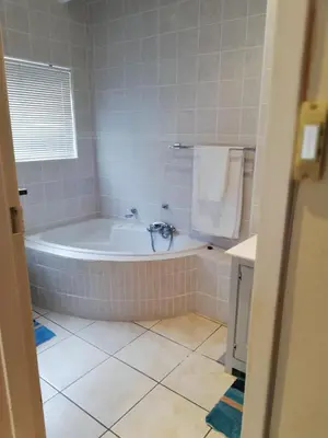 a bathroom with a tub and a tiled floor at C the C - Holiday Home in Hermanus
