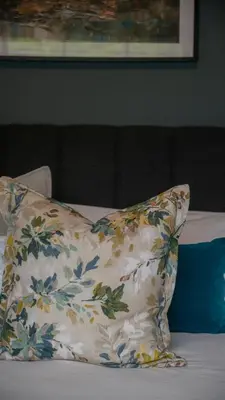 a pillow sitting on top of a bed with a flower pattern at Hoogwater Garden Cottage in Wolseley