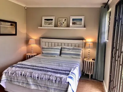a bedroom with a bed with two lamps and pictures at The West Wing guest suite. Pringle Bay. in Pringle Bay