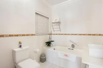 a white bathroom with a toilet and a sink at Kwantu Guesthouse 1 in Cape Town