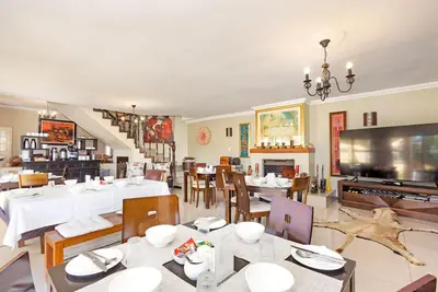 a dining room with tables and chairs and a television at Kwantu Guesthouse 1 in Cape Town