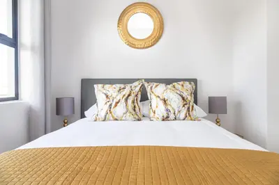 a bedroom with a white bed with a mirror on the wall at 6 Atlantic Port - Cosy, modern 2-bedroom apartment - Blouberg in Bloubergstrand
