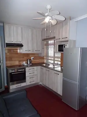 a kitchen with wooden cabinets and a white refrigerator at Khaya B&B Mandalay in Cape Town