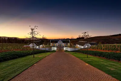 a driveway leading to a house with a sunset in the background at Brookdale Estate - Manor House in Paarl