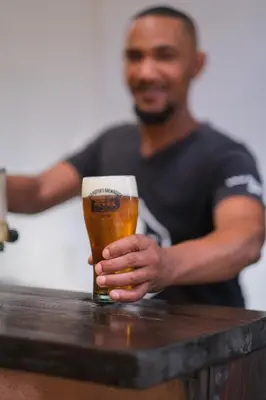 a man sitting at a table holding a glass of beer at Old Potters Inn in Greyton
