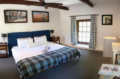 a bedroom with a bed with a blue headboard and a window at Old Potters Inn in Greyton