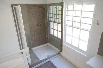 a bathroom with a shower and a window at Old Potters Inn in Greyton