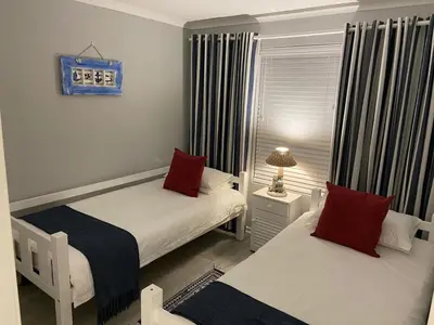 a small bedroom with two beds with red pillows at CView in Hermanus