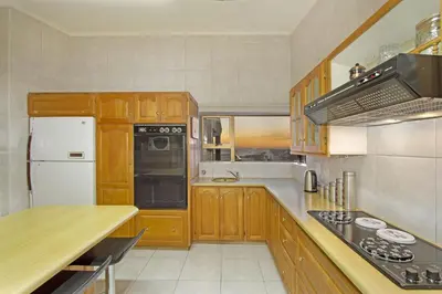 a kitchen with wooden cabinets and a white refrigerator at Zaria Sun Penthouse in Cape Town