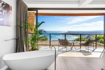 a bathroom with a tub and a view of the ocean at Zaria Sun Family in Cape Town