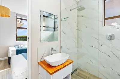 a white bathroom with a sink and a shower at Zaria Sun Family in Cape Town