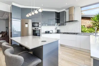 a kitchen with white cabinets and a white counter top at Zaria Sun Family in Cape Town