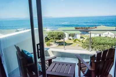 a balcony with chairs and a view of the ocean at Whale Rock 40 in Hermanus