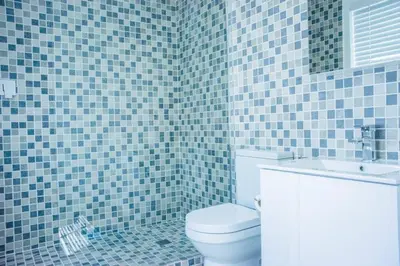 a blue tiled bathroom with a toilet and a sink at Whale Rock 40 in Hermanus