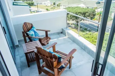 two rocking chairs on a balcony with a view at Whale Rock 40 in Hermanus