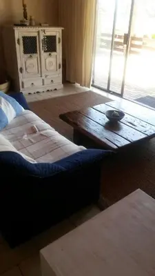a living room with a couch and a wooden table at Lagoon Edge in Hermanus