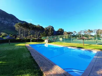 a swimming pool in a yard with a tennis court at Lagoon Edge in Hermanus