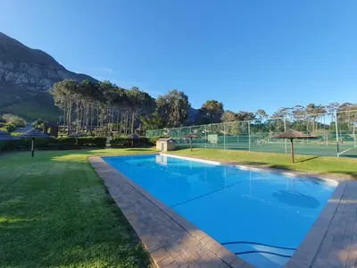 a swimming pool in a yard with a tennis court at Lagoon Edge in Hermanus