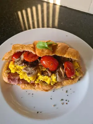 a sandwich with tomatoes and eggs on a white plate at Cape Winelands Business Villas in Joostenberg Vlakte