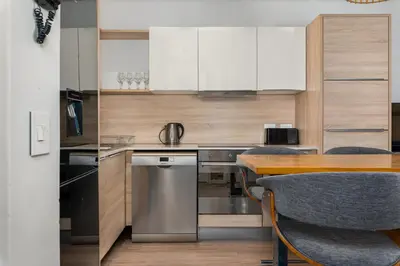a kitchen with white cabinets and a wooden table at Matrix Apartments in Cape Town