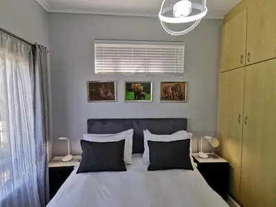 a bedroom with a bed with two pillows and a window at Guinea Fowl Self Catering in Cape Town