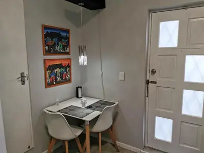 a room with a table and two chairs and a door at Guinea Fowl Self Catering in Cape Town