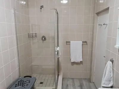 a bathroom with a shower with a glass door at Guinea Fowl Self Catering in Cape Town