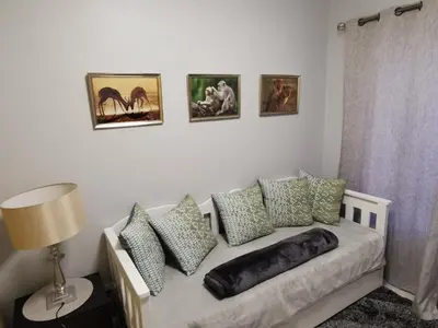 a living room with a couch with pillows and pictures on the wall at Guinea Fowl Self Catering in Cape Town