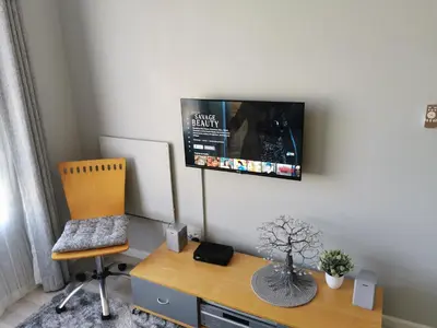 a living room with a tv on the wall at Guinea Fowl Self Catering in Cape Town