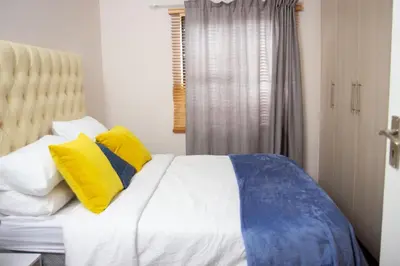 a bedroom with a bed with yellow and blue pillows at Wilcre's blouberg home in Cape Town