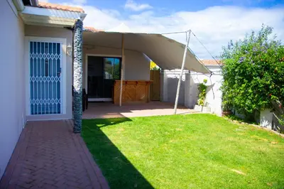 a house with a patio and a grass yard at Wilcre's blouberg home in Cape Town