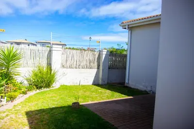 a backyard with a white fence and a yard at Wilcre's blouberg home in Cape Town