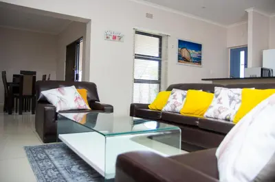 a living room with two couches and a glass table at Wilcre's blouberg home in Cape Town