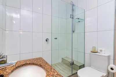 a bathroom with a glass shower with a toilet at Hermanus Beachfront Lodge - Solar Power in Hermanus
