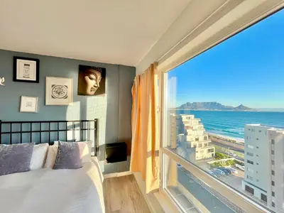 a bedroom with a large window with a view of the ocean at Ocean View Apartment in Cape Town