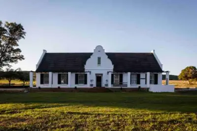 a white house with a black roof in a field at De Goede Hoop Farmstead in Wilgerhof