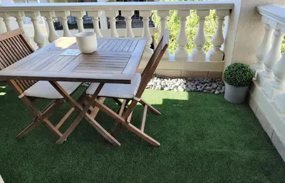 a wooden table and chairs on a balcony with grass at The CoziPlace in Cape Town