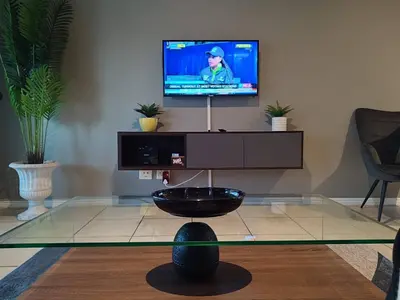 a living room with a tv and a glass table at The CoziPlace in Cape Town