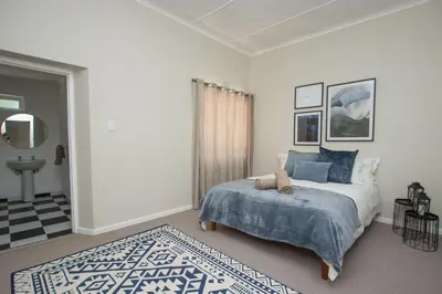 a white bedroom with a bed and a rug at Hoogwater Family House in Wolseley